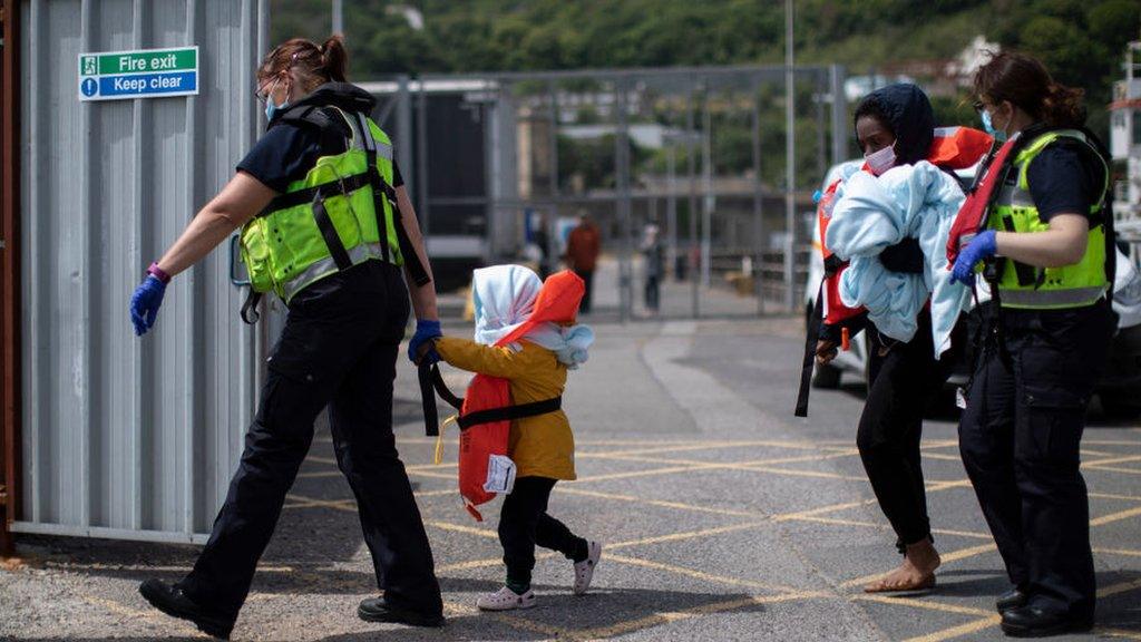 A young child is led to an intake facility after arriving in Kent