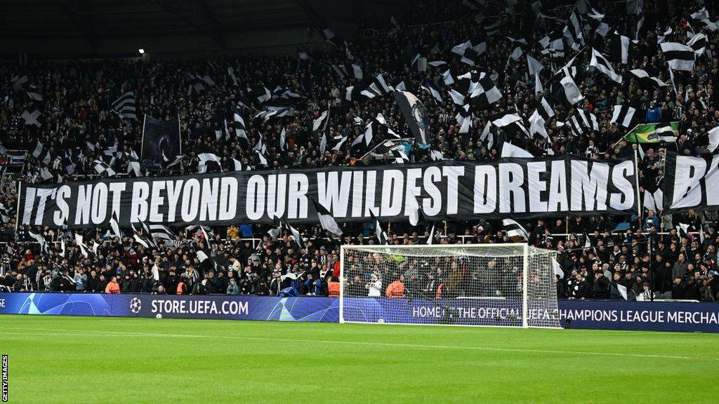 Newcastle fans hold up a banner before the AC Milanb game