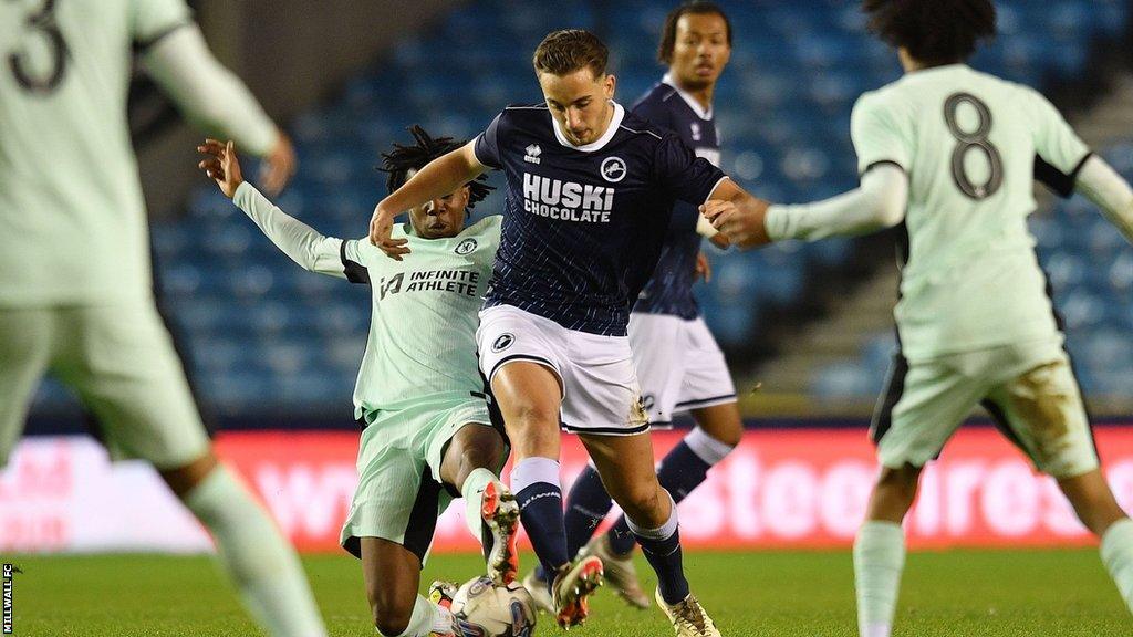 A Millwall player dribbles through several Chelsea tackles in midfield