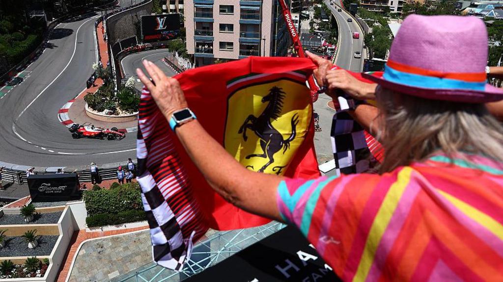 A fan flies a Ferrari flag as Charles Leclerc comes around the hairpin during Monaco Grand Prix first practice