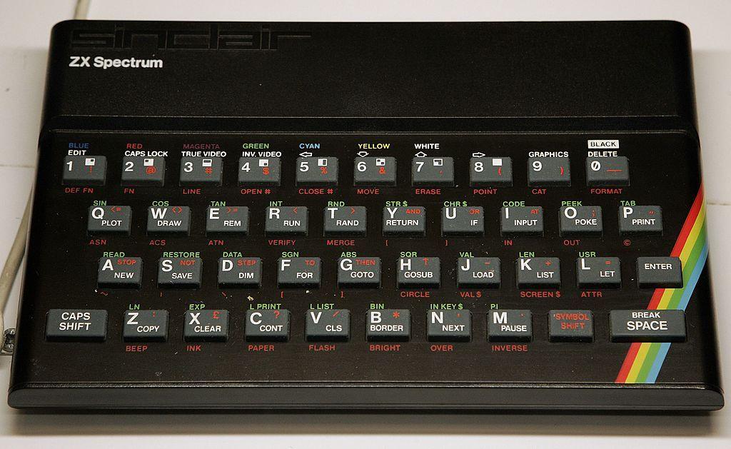 A ZX Spectrum home computer. It is black with grey rubber keys and a rainbow stripe across the body.