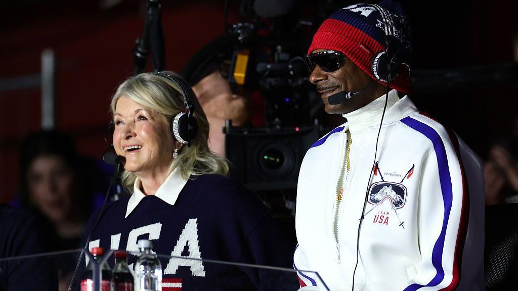 Martha Stewart in a navy USA jumper and Snoop Dogg in a white USA tracksuit wearing headsets as they broadcast from the Winter Olympics