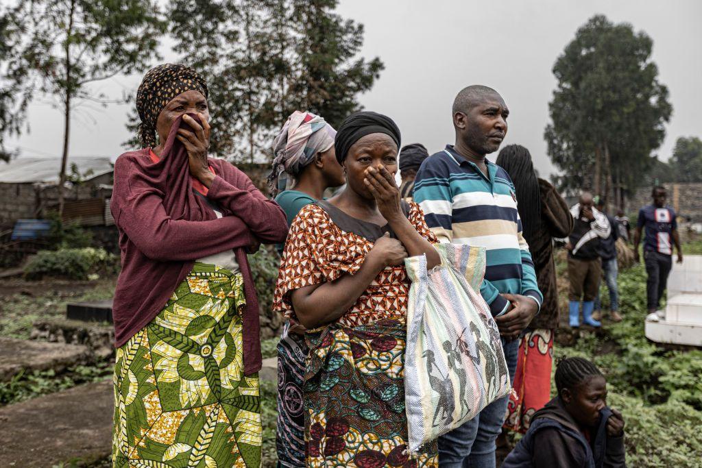 Two women cover their mouths as their friends and relatives are buried following the capture of Goma by M23 rebels