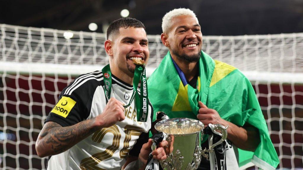Newcastle midfielders Bruno Guimaraes and Joelinton holding the EFL Cup