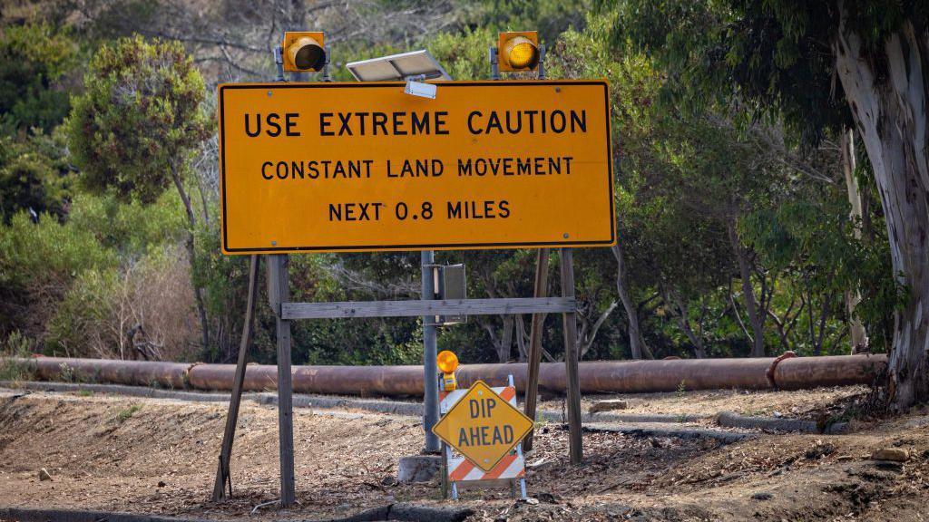 A sign warns of 'constant land movement'