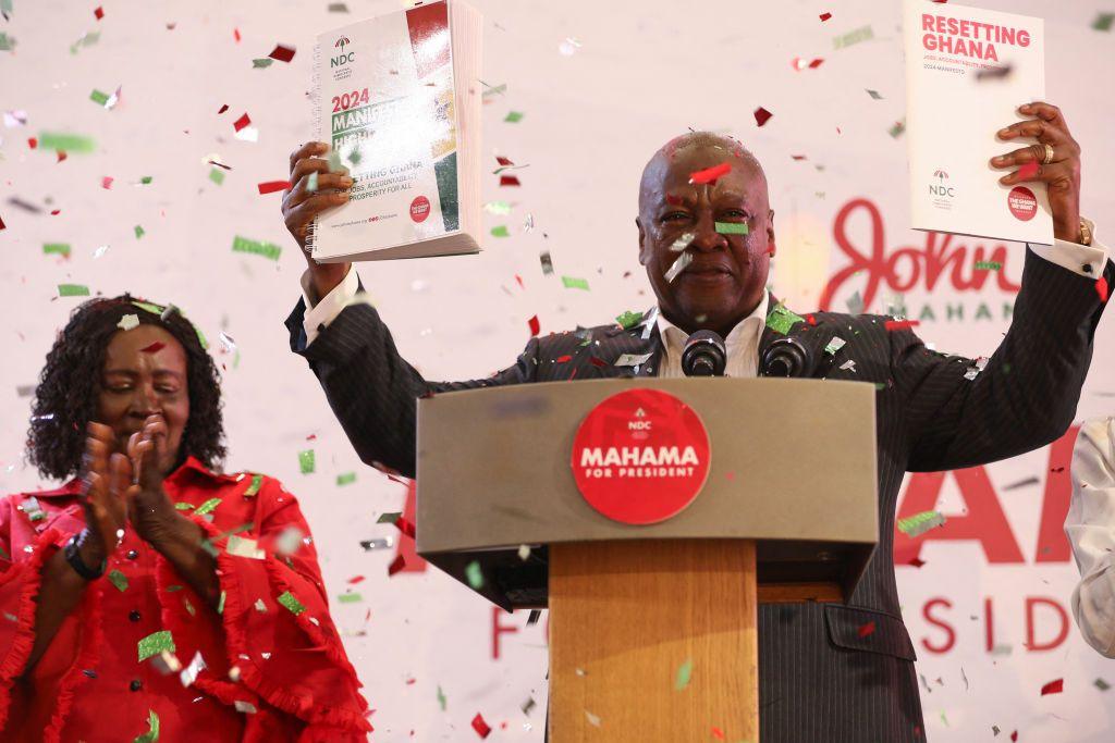 John Mahama (R), holds a copy of the party's manifesto as his running mate Jane Naana Opoku-Agyemang (L),  looks on in Winneba, Ghana, on August 24, 2024