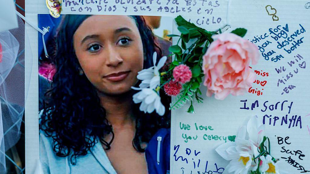 A handmade poster showing a photo of teenager Celeste Rivas Hernandez is surrounded by handwritten messages and flowers at at a memorial in her hometown of Lake Elsinore, California.