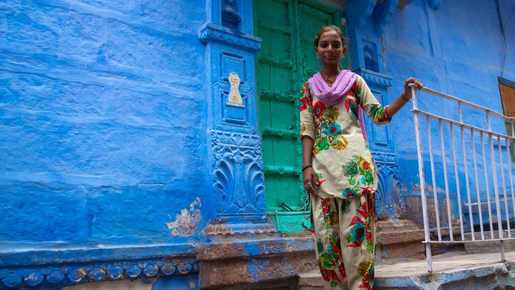 Portrait of a rajasthani teenage girl in traditional sari in front of a blue house, Rajasthan, Jodhpur, India on July 20, 2019 in Jodhpur, India.