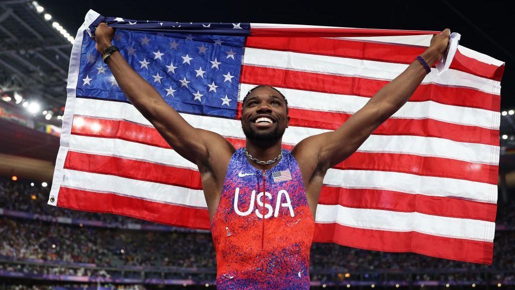 Noah Lyles holding the US flag.