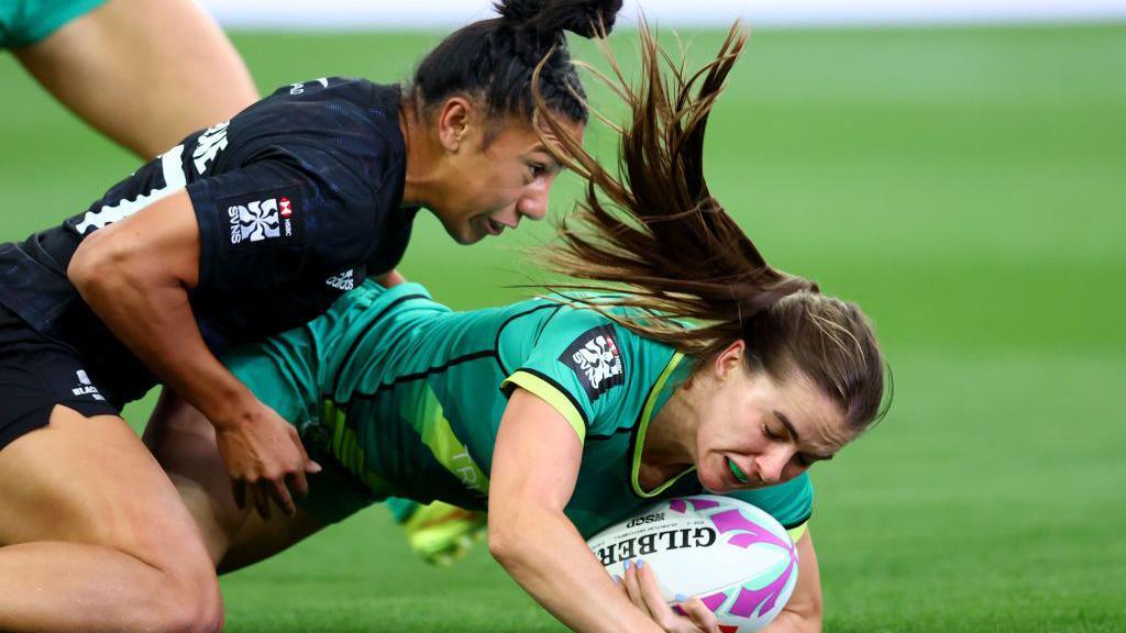 Two rugby players with the ball on the ground