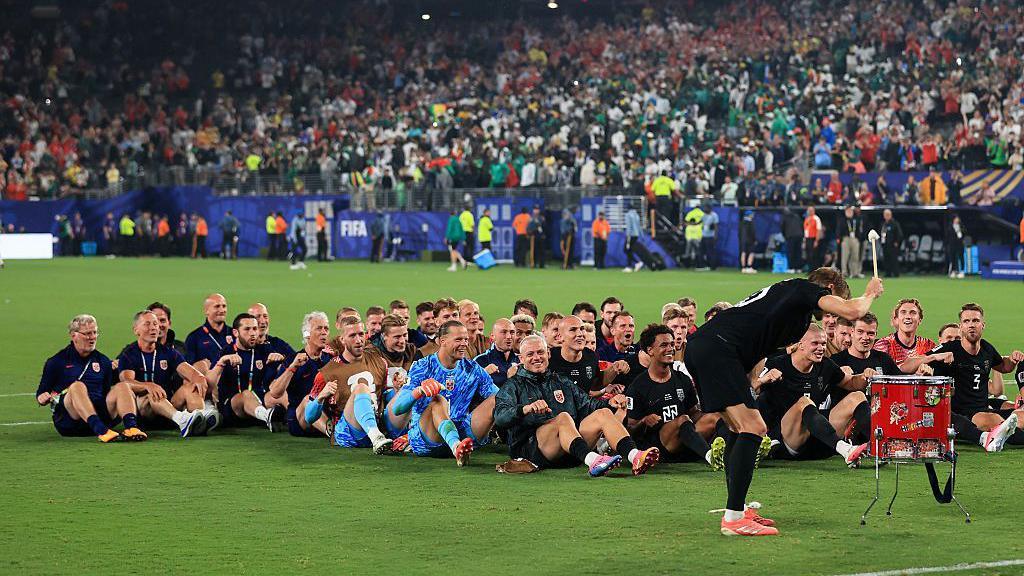 Norway captain Martin Odegaard bangs the drum as the rest of the Norway squad do their 'Viking row' celebration after beating Senegal. 