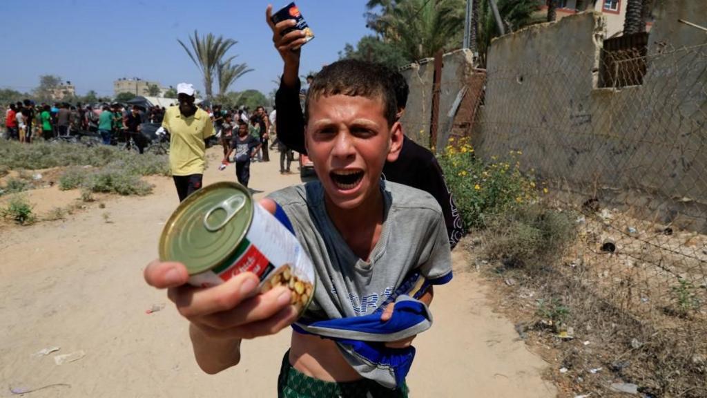 A Palestinian youth holds a can of chickpeas from an aid package dropped from an airplane