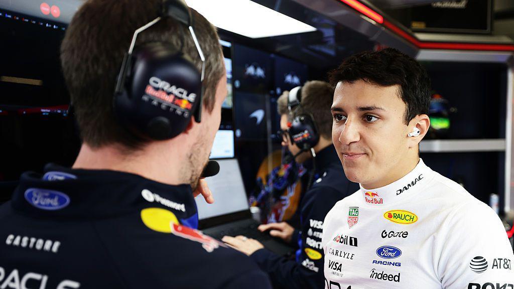 Isack Hadjar chats to a Red Bull engineer in the garage during the British Grand Prix 