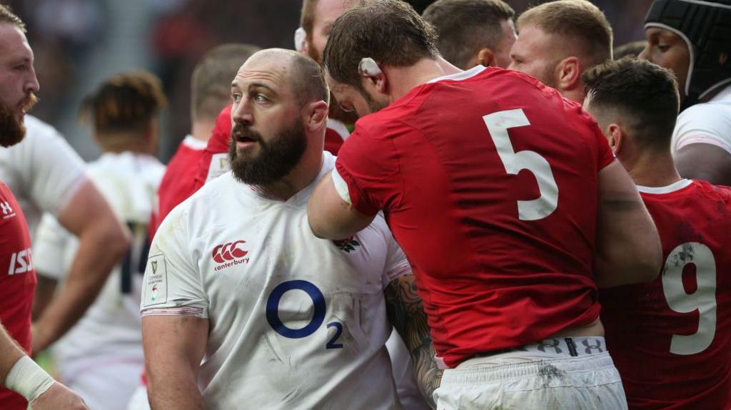 Joe Marler grabs Alun Wyn Jones in a crowd of players.