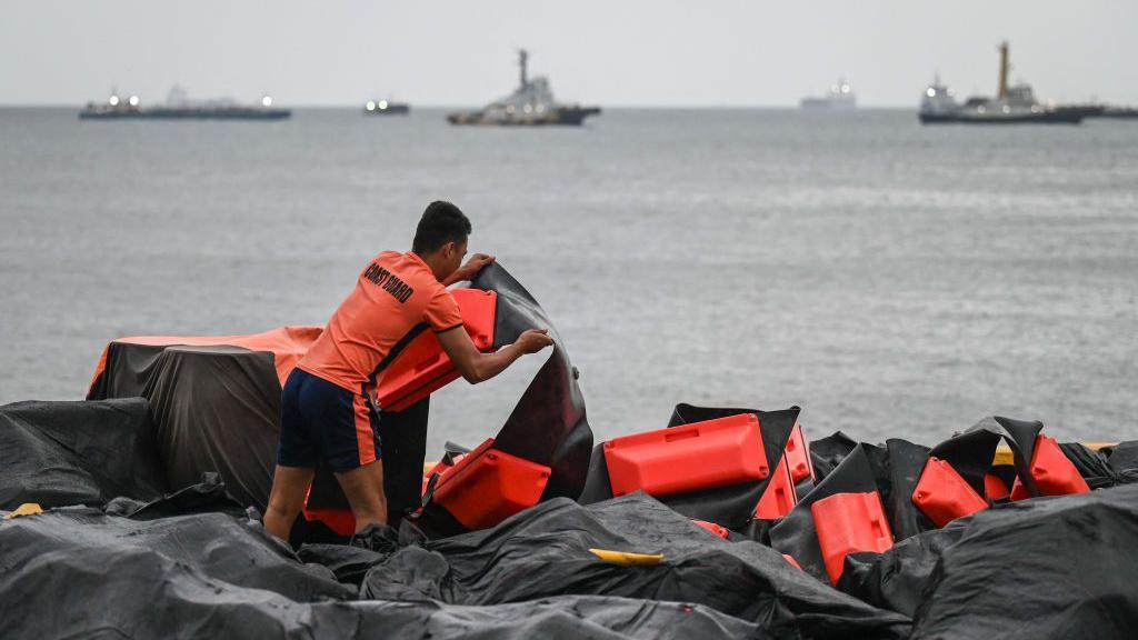 Coast guard arranging an oil spill containment near the water. 