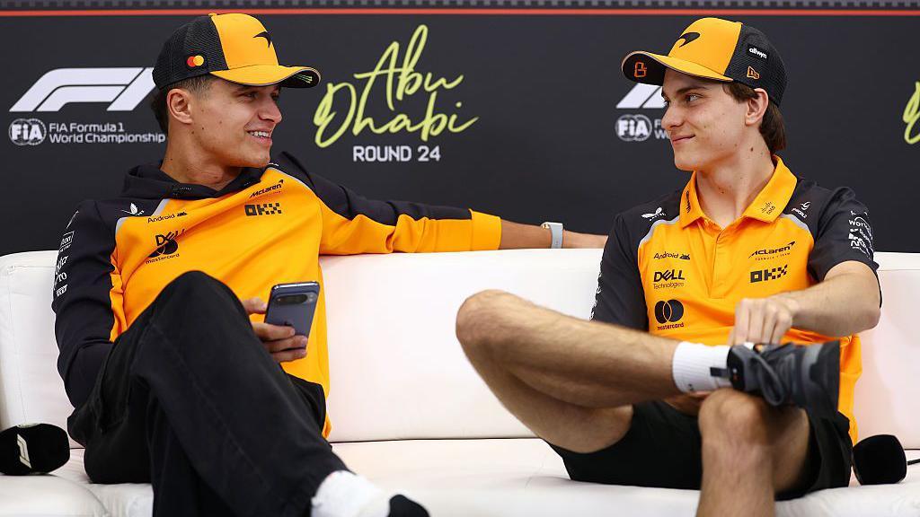 Lando Norris and Oscar Piastri look at each other during the news conference in Abu Dhabi