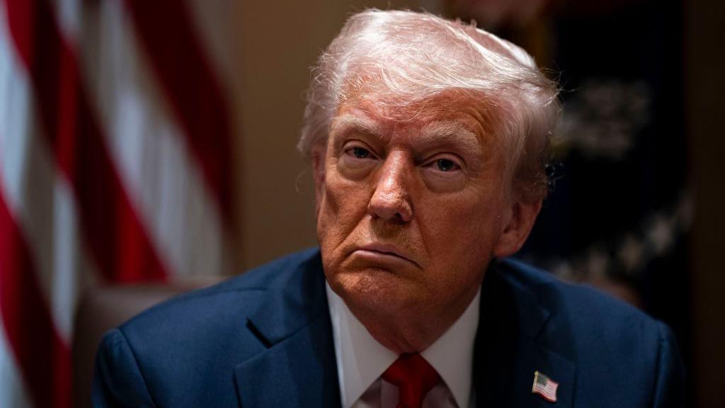 Donald Trump wearing a suit jacket with a pin of an American flag