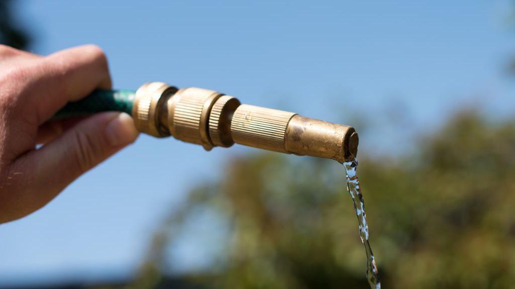 A person holding a hosepipe.