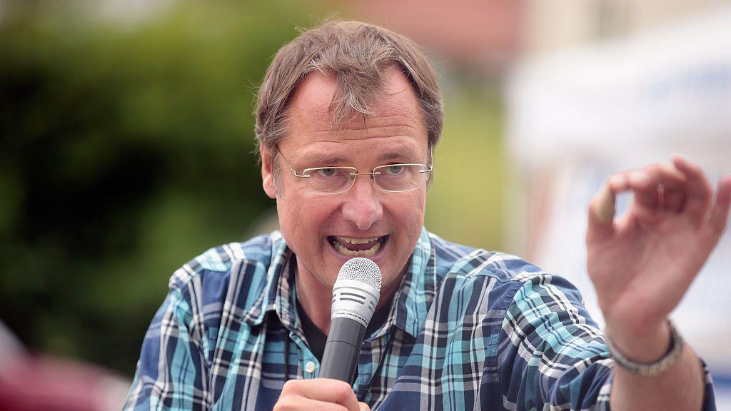 Michael Stuerzenberger holds microphone gesturing with his hand in June 2015 in Pfaffenhofen an der Ilm, Germany. 