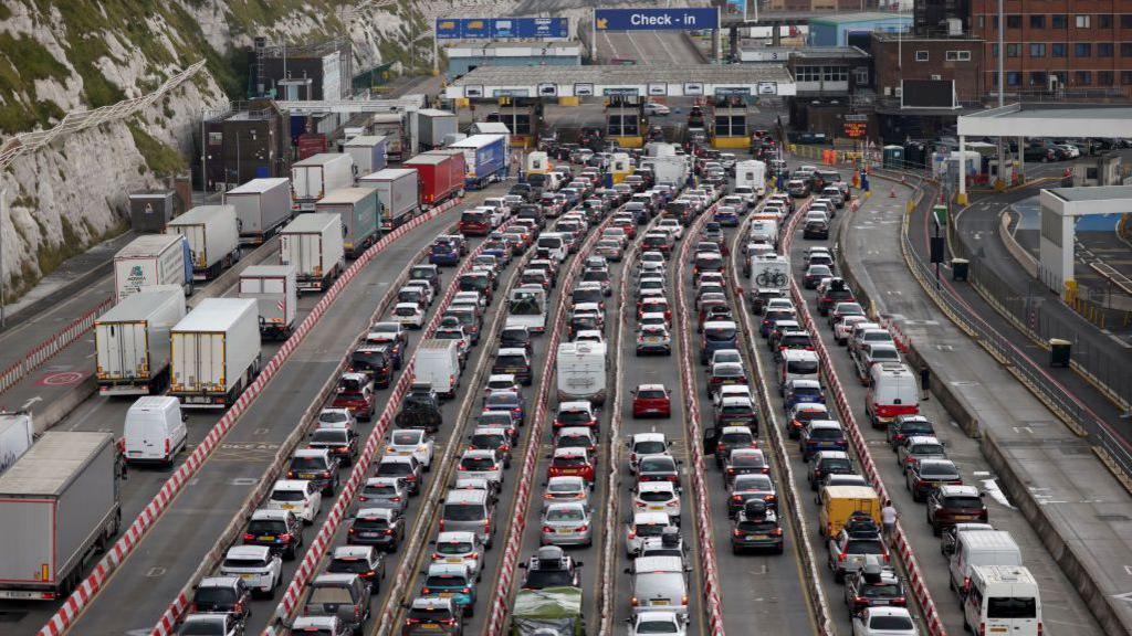 Many vehicles queuing outside a border check at a port. 