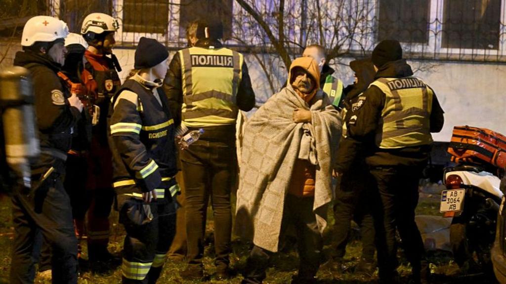 A resident is help by emergency personnel outside his damaged residential building following Russian missiles and drones strikes in Kyiv