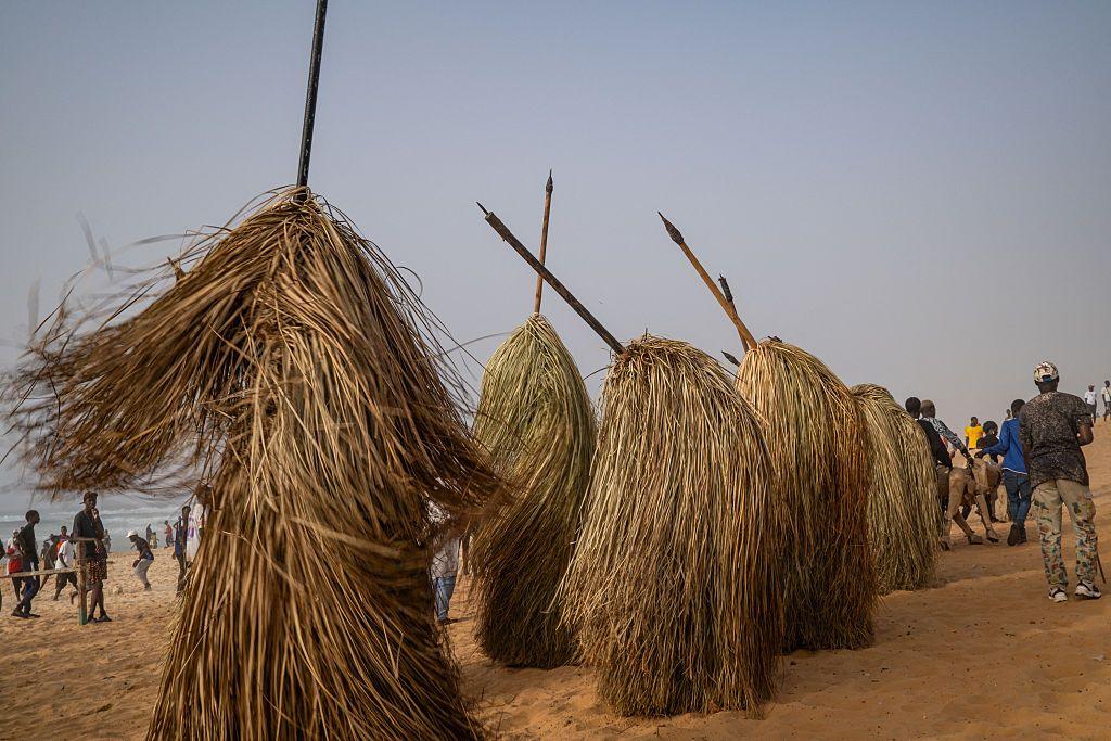 People covered in long straw costumes dance in unison.