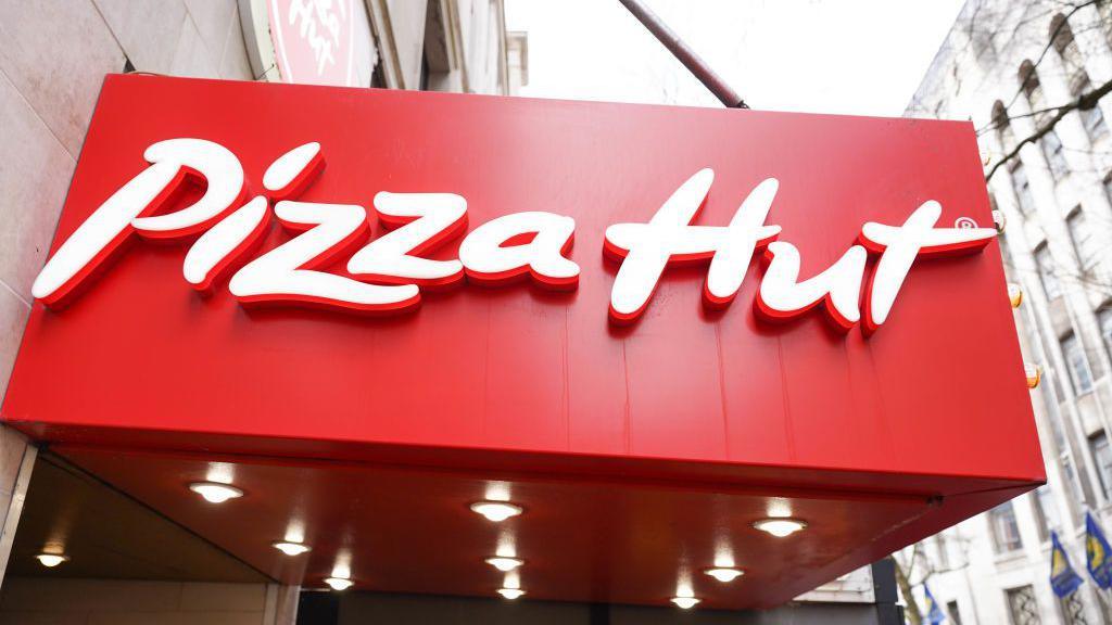 A bright red Pizza Hut logo on the side of a building 