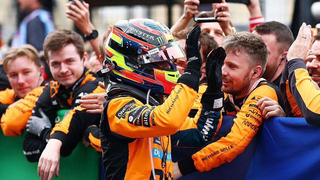 Oscar Piastri gives high fives to his McLaren team members after coming second at Suzuka 