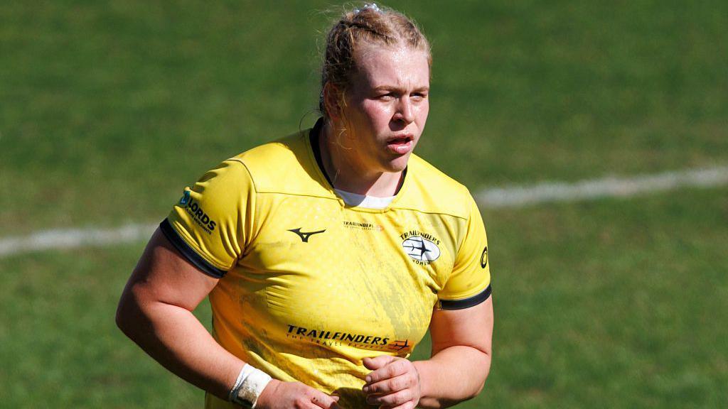 Abi Burton looking on wearing Trailfinders' away yellow kit
