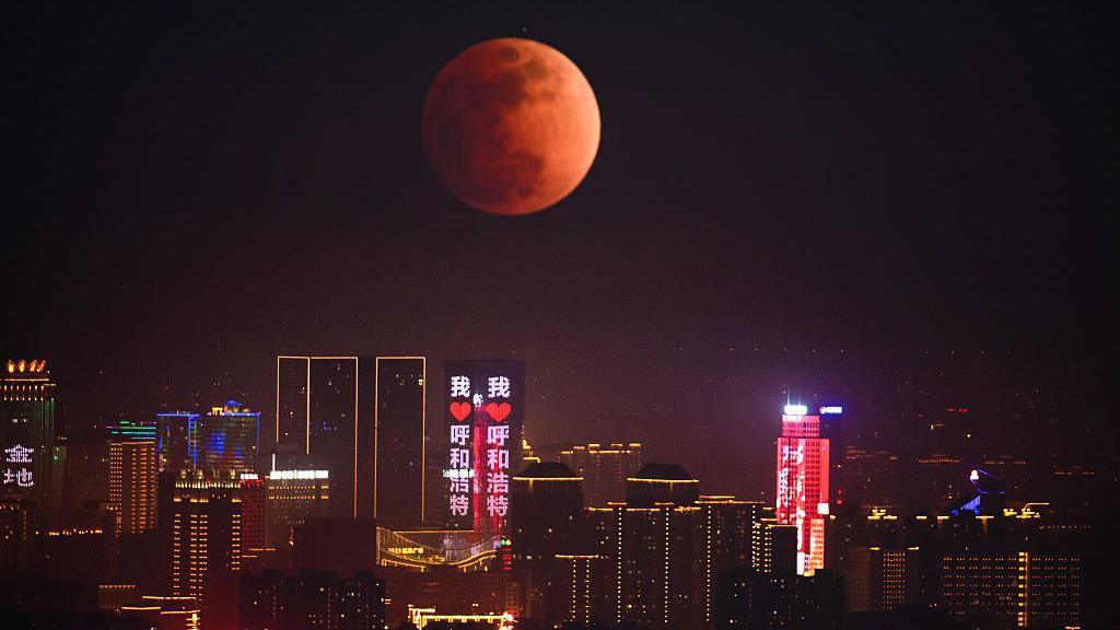 A red moon lights up a city skyline