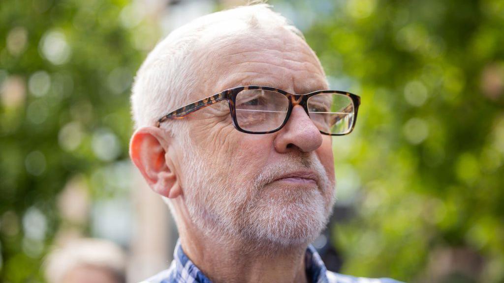 Jeremy Corbyn wearing glasses and a plaid shirt 