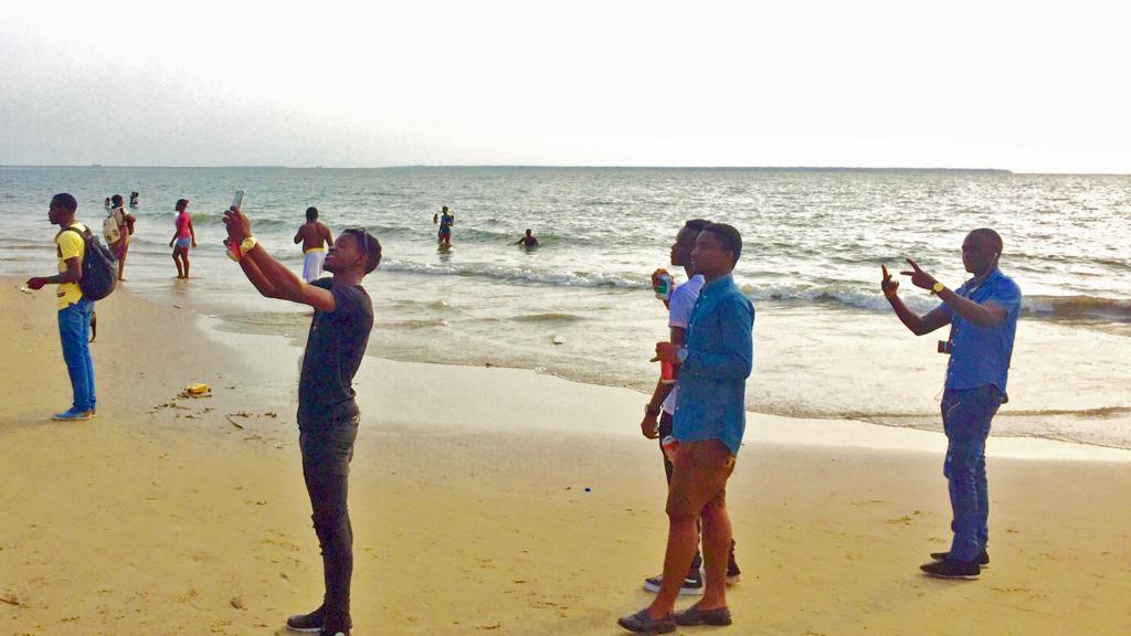 Men taking selfies on a beach in Gabon