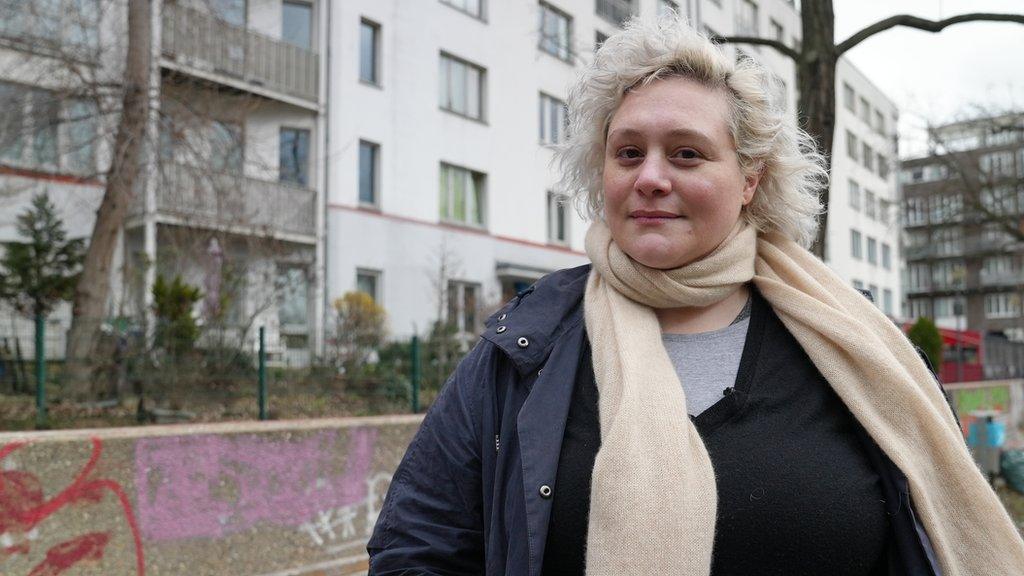 Ana di Lisio looks at the camera in front of flats in Berlin