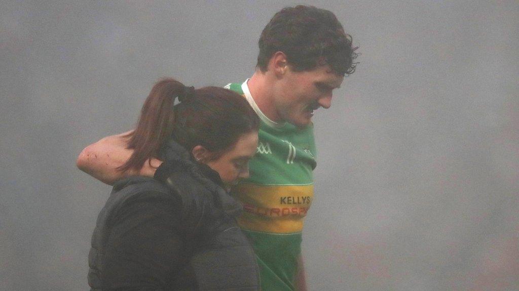 Jack Doherty is helped off the pitch at a fog-bound Newry after suffering an ankle injury