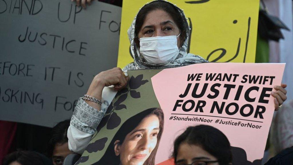 A woman holds a sign saying "justice for Noor"