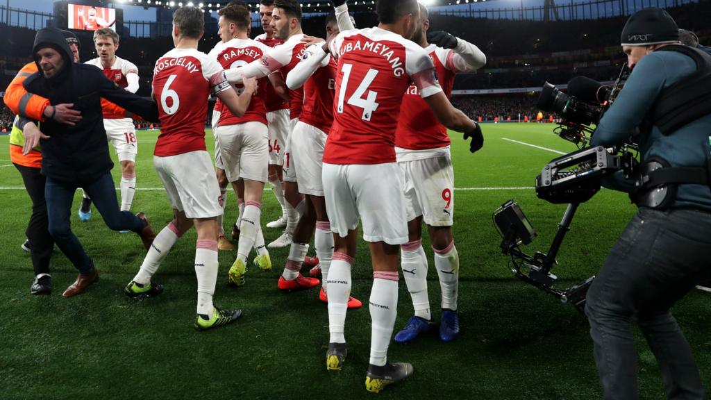 Arsenal celebrate as a spectator runs on the pitch