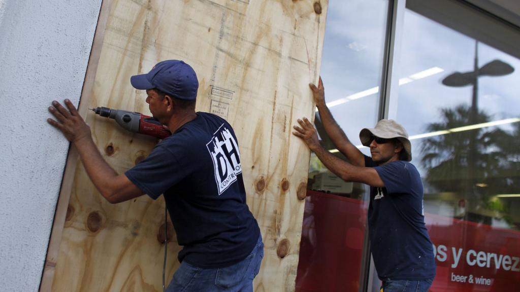 People board up windows of a business in preparation for the anticipated arrival of Hurricane Maria in San Juan, Puerto Rico on September 18, 2017