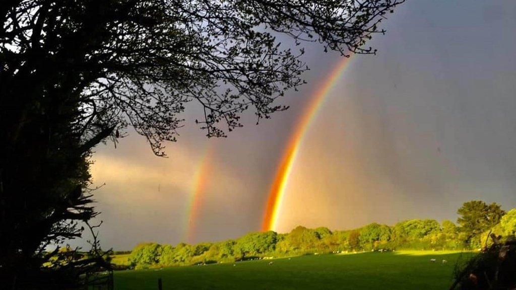 A double rainbow over fields as the sun sets