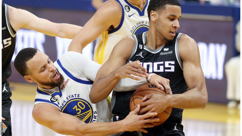 Stephen Curry and Keegan Murray contest the ball