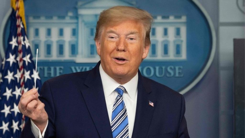 Donald Trump holds up a medical swab at a White House press briefing, 19 April 2020