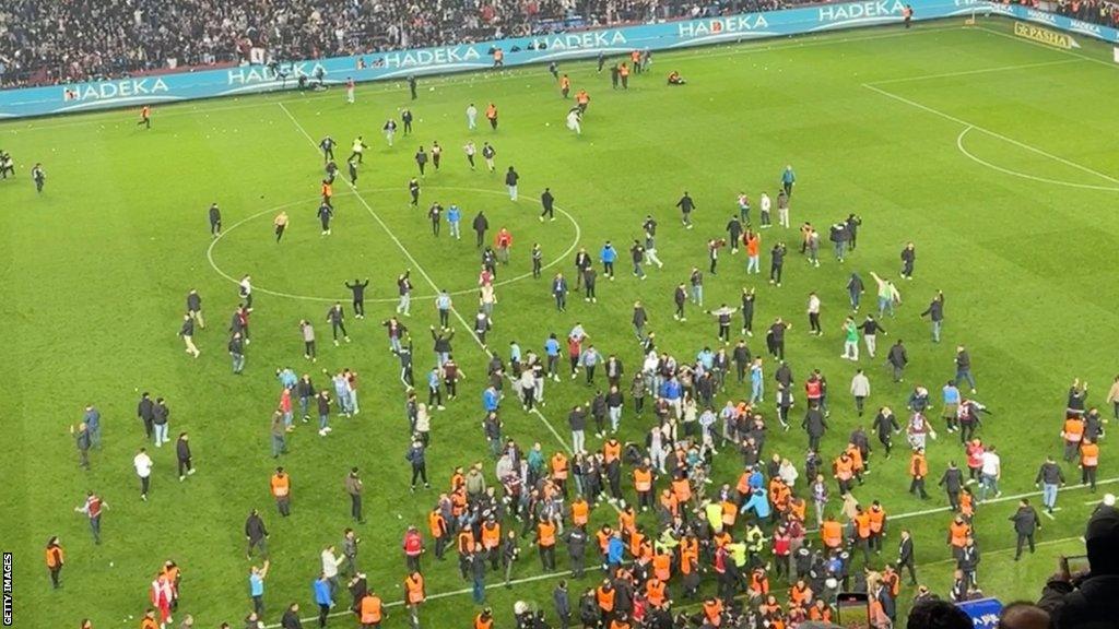 Trabzonspor fans running onto the pitch and attacking Fenerbahce players