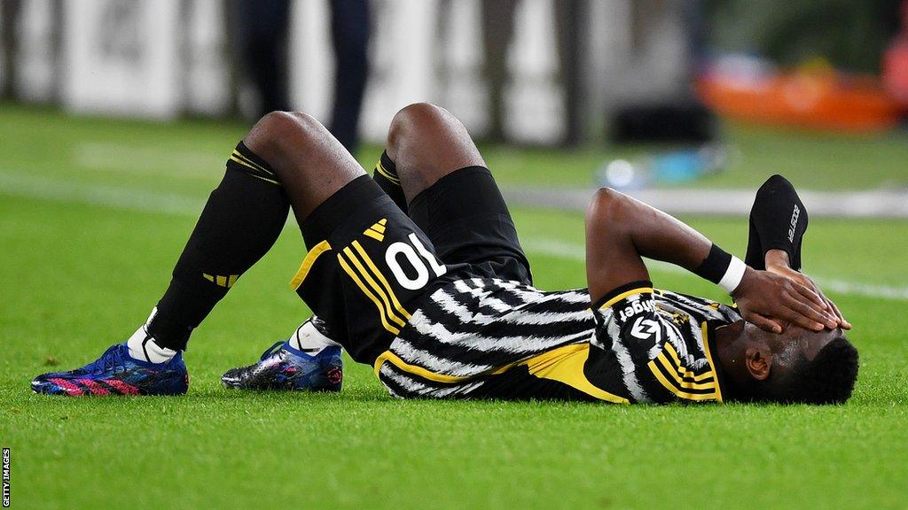 Juventus midfielder Paul Pogba covers his face with his hands as he lays on the pitch injured