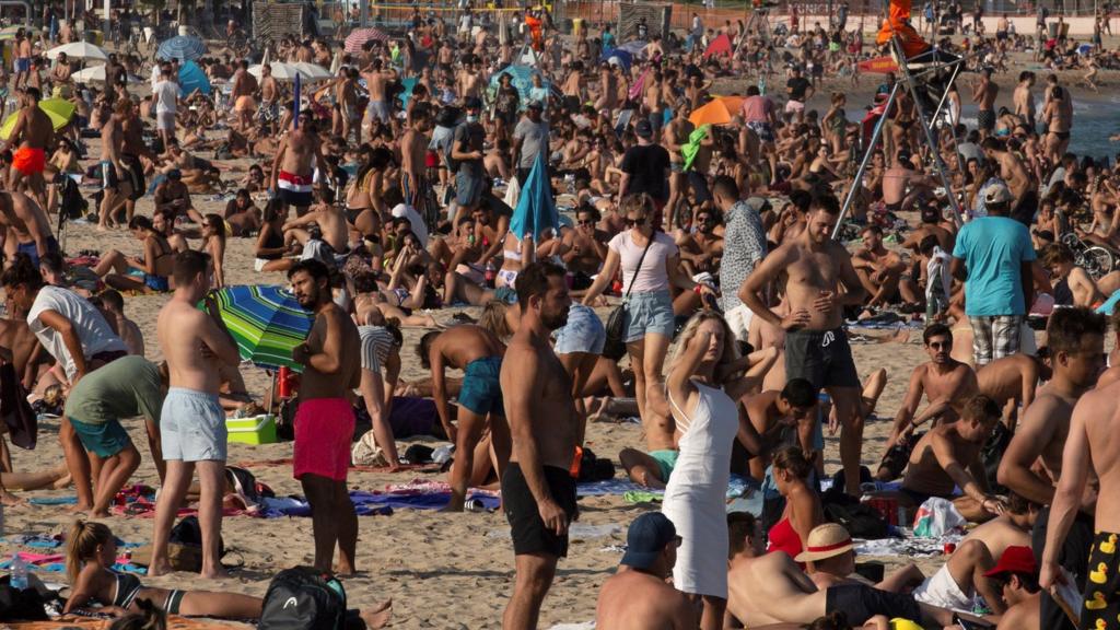 Beachgoers bask in the sun as they enjoy a warm afternoon in Barcelona on 17 July