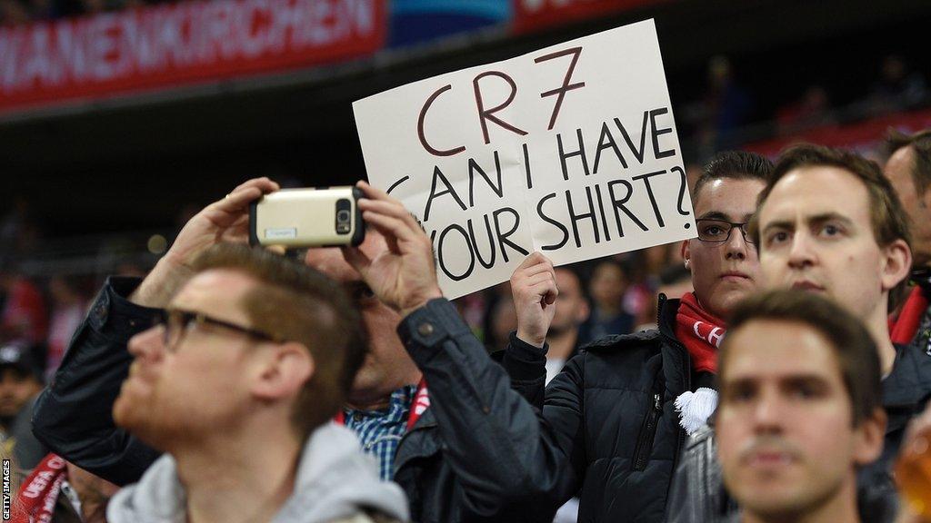 A football fan hold a sign asking for the shirt of a player