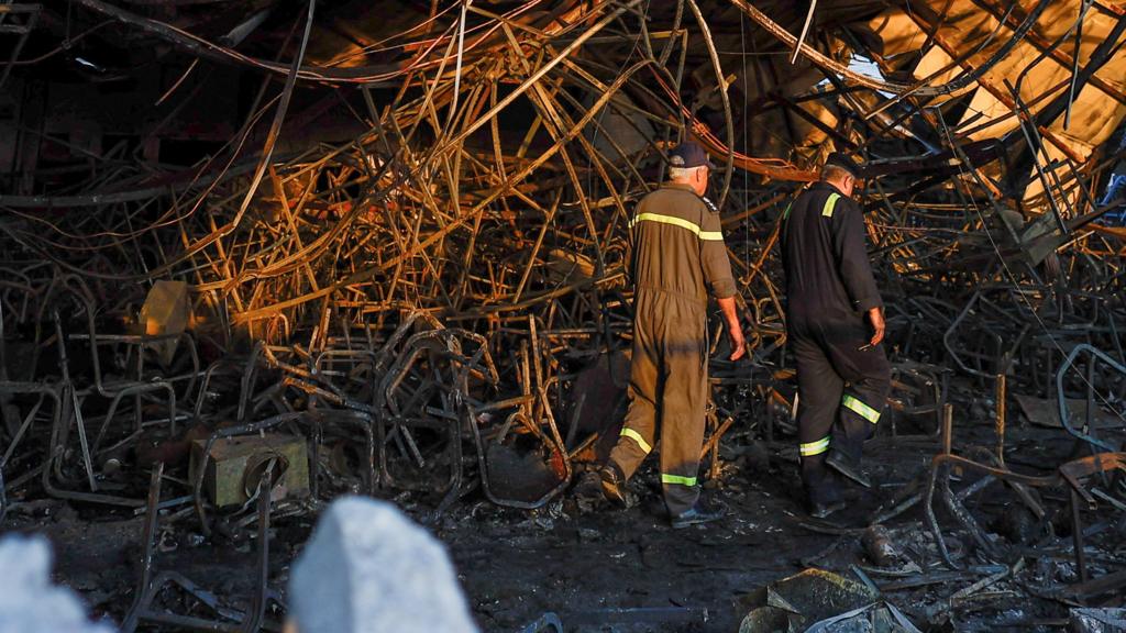 Officials walk through the rubble at the site following a fatal fire at a wedding celebration, in the district of Hamdaniya in Iraq's Nineveh province, Iraq, on 27 September 2023