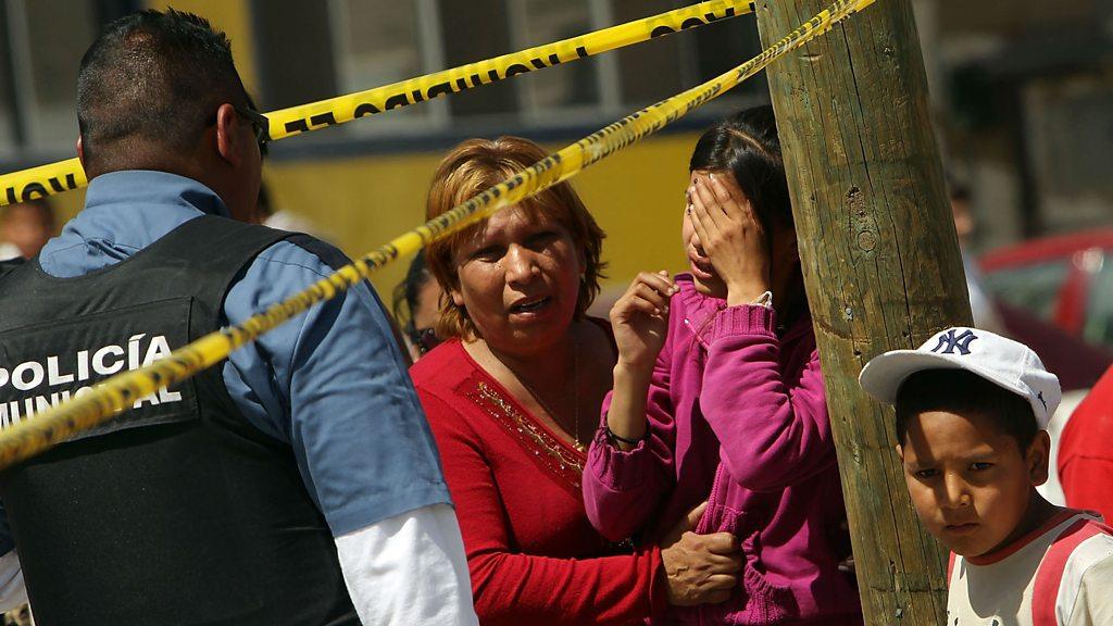 Family members cry in front of a car in which two men lay dead