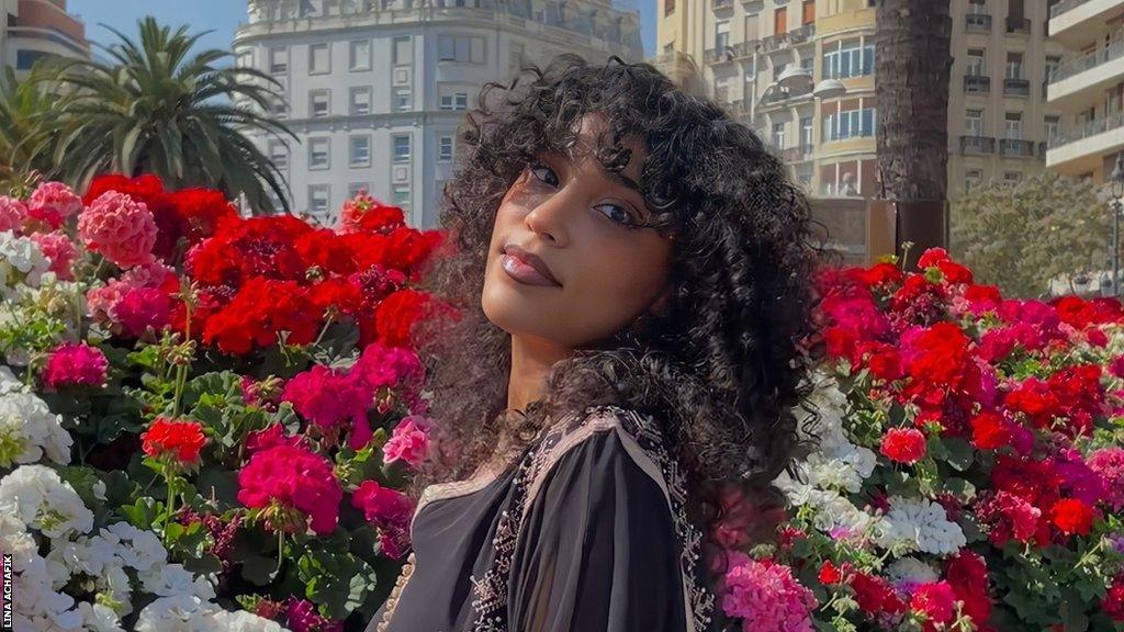 Student Lina Achafik posing in front of flowers