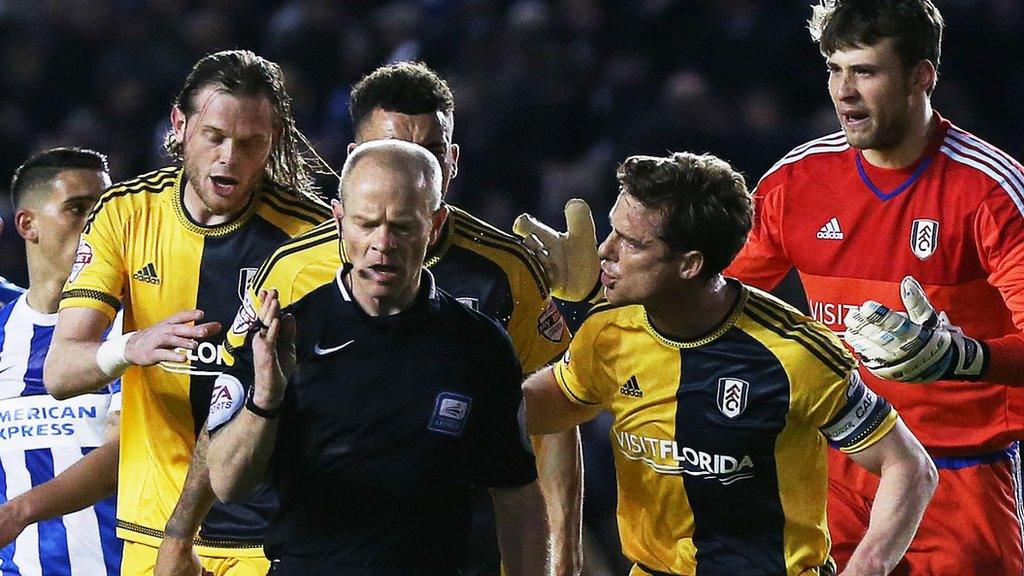 Fulham players surround referee Andy Woolmer