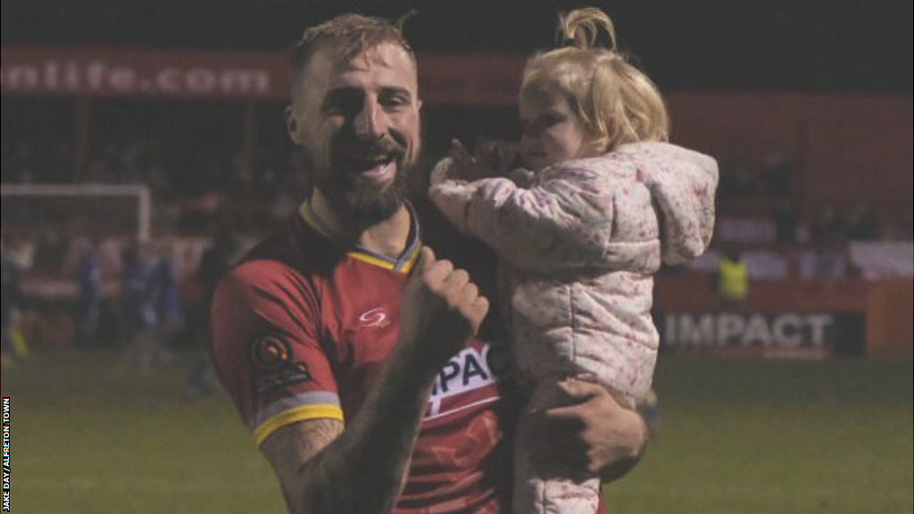 Jake Day celebrates on the pitch with his daughter Lydia after Alfreton Town reach the second round of the FA Cup