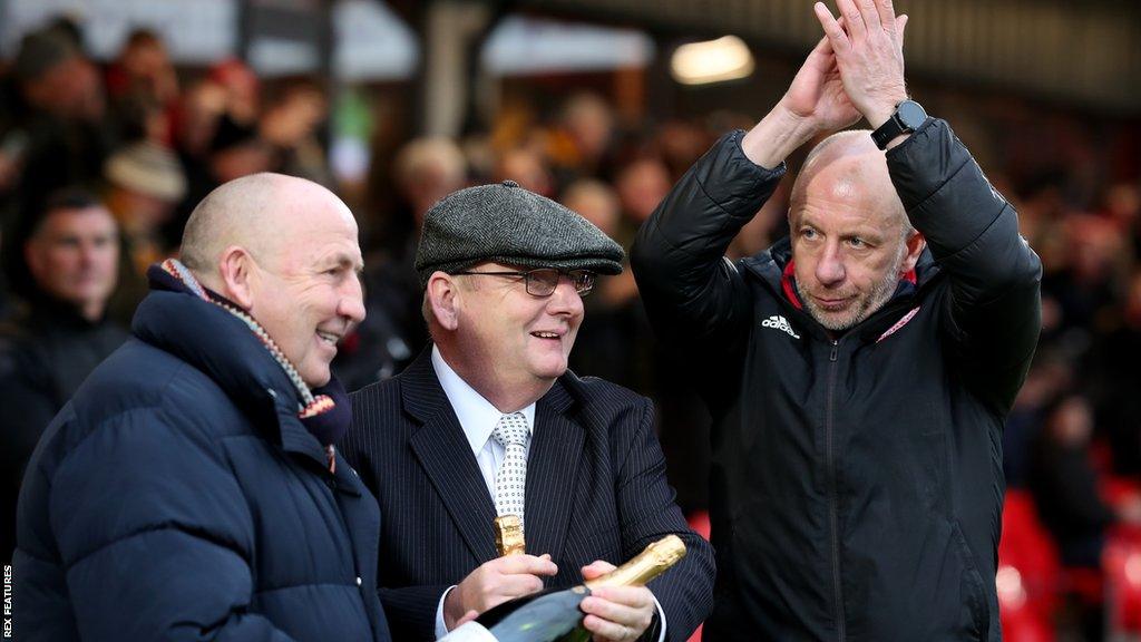 John Coleman receives a bottle of fizzy wine from chairman Andy Holt